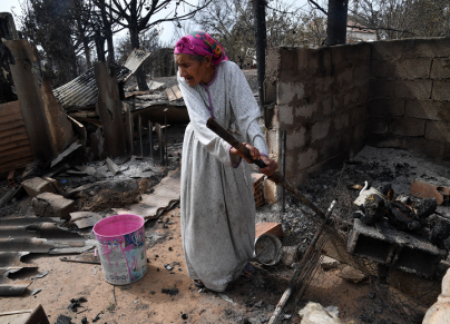 مسنة تقف على أنقاض بيتها الذي اتت عليه الحرائق بولاية الطارف (الصورة:Getty)