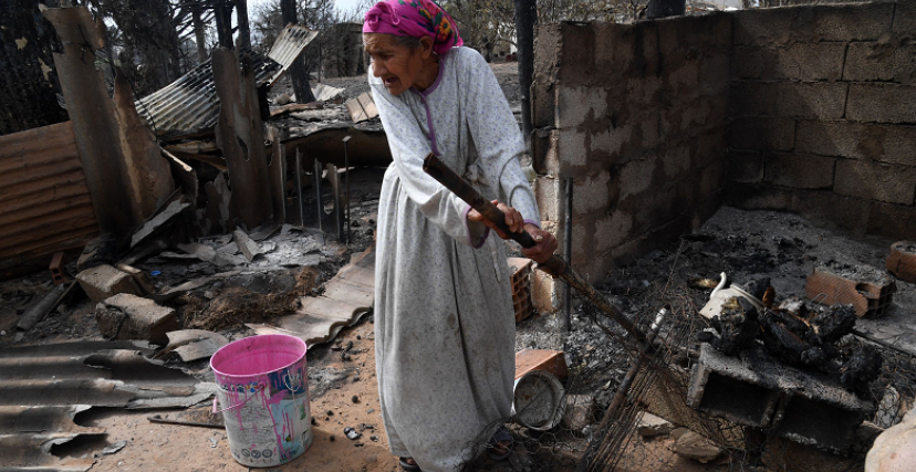مسنة تقف على أنقاض بيتها الذي اتت عليه الحرائق بولاية الطارف (الصورة:Getty)