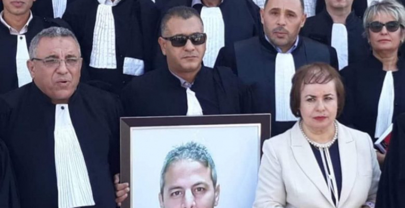 المحامي عيسى رحمون يحمل صورة أحد المعتقلين (فيسبوك/الترا جزائر)